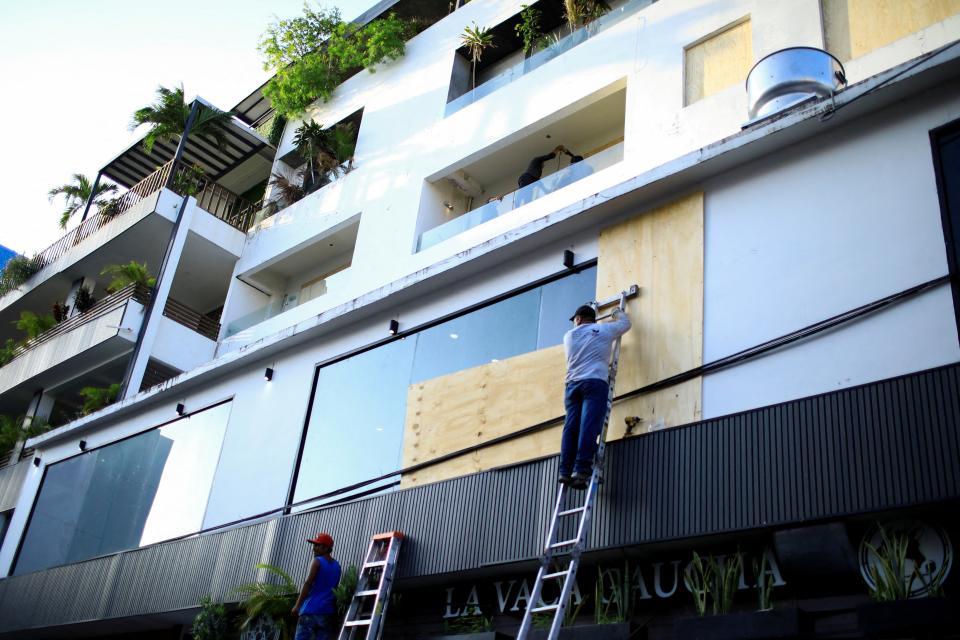 A worker installs wood boards on a building's windows ahead of Hurricane Beryl, in Playa del Carmen, Mexico (REUTERS)