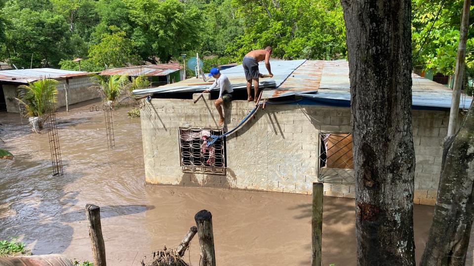Residents work to repair the roof of a flooded building in Venezuela after Hurricane Beryl blew through the region (AFP via Getty Images)