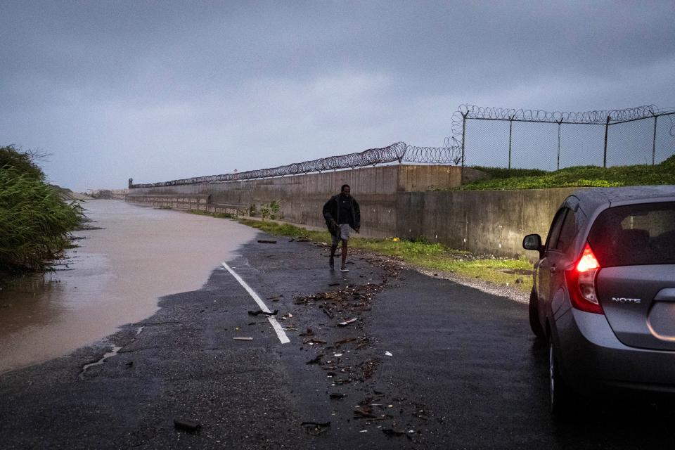 A man walks towards his car after assessing a flooded road as Hurricane Beryl hits the southern coast of the island, in Kingston, Jamaica (REUTERS)